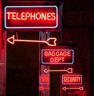 Telephones, Baggage department and Security in capital letters in red neon signs.