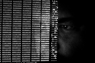A man's face obscurred by a flow of binary numbers.