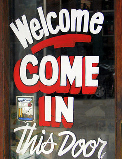 'Welcome.   achieve in this Door' elegantly painted onto a glass door frame.